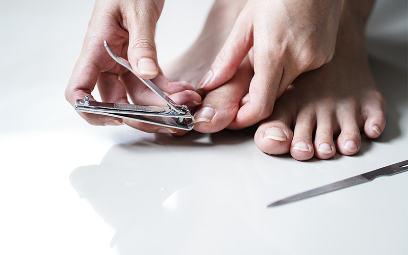 Person clipping a toenail to maintain foot hygiene.