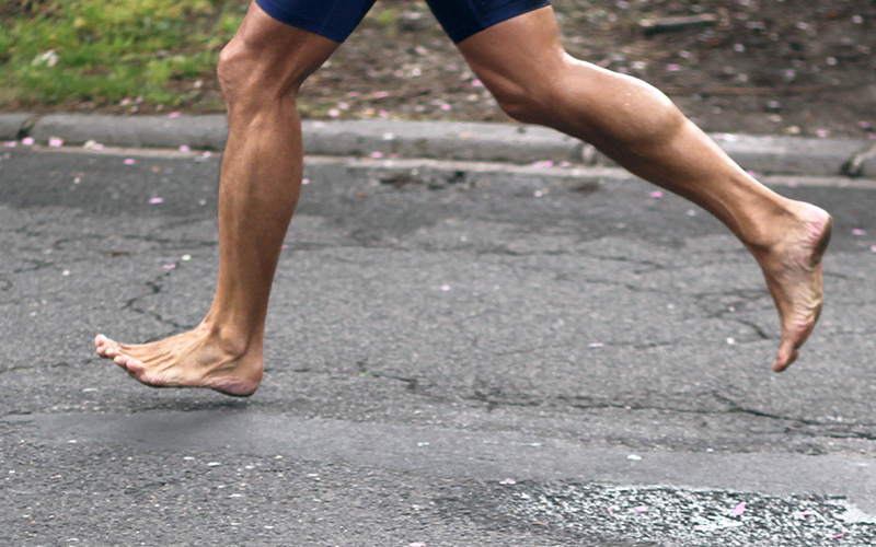 Barefoot person running on asphalt.