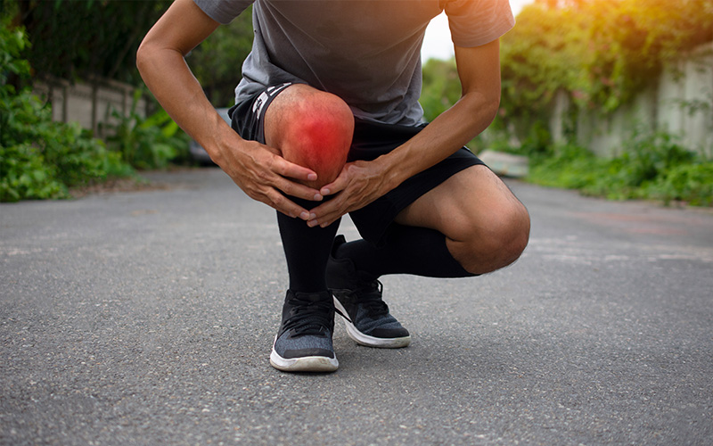Runner holding knee in pain while training.